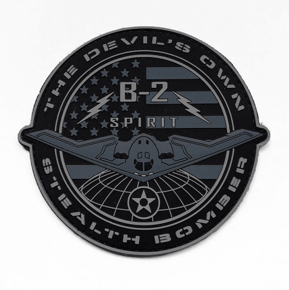 A round black patch featuring the text 'B2 SPIRIT' and 'THE DEVIL'S OWN STEALTH BOMBER' with a graphic of an airplane and the American flag.